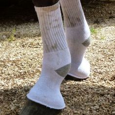 a person standing on top of a wooden post with socks over their ankles and feet