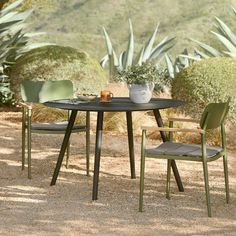 a table with two chairs and a potted plant on top of it in the middle of a gravel area