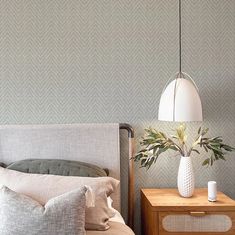 a bed room with a neatly made bed and a vase on top of the headboard