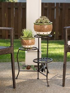 three potted plants sitting on top of two metal planters next to a white pole