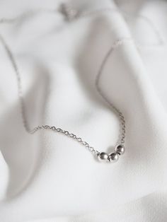 A simple and minimal piece, this tiny bead necklace is sure to become an everyday staple for layering.  3 little satin finish round beads slide freely along delicate chainMATERIALStarnish resistant rhodium silver filled or gold filled charm & chainDIMENSIONS40.6cm (16") plus 2" extender chain, each bead measures 4mm (5/32") diameter◊ Matching sphere jewelry: https://www.etsy.com/shop/kindlingandco/search?search_query=ball◊ More dainty charm necklaces: https://www.etsy.com/shop/kindlingandco? Minimalist Everyday Jewelry With Ball Chain, Everyday Minimalist Jewelry With Ball Chain, Everyday Minimalist Ball Chain Jewelry, Minimalist Necklace With Ball Chain And Round Beads, Minimalist Jewelry With Satellite Chain, Minimalist Sterling Silver Necklace With Round Beads, Tiny Bead Necklace, Necklaces Personalized, 3 Daughters