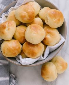 a bowl filled with rolls sitting on top of a table next to a towel and napkin