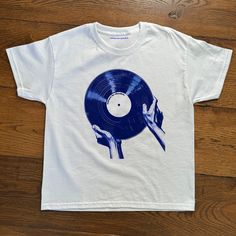 "The Record" Baby Tee Baby tee featuring iconic record graphic.  - 100% cotton - Classic fit - Runs true to size (refer to size chart) - Tear-away label - Y2K Vintage Streetwear Trending Fashion - Environmentally sustainable made-to-order system Baby tee's were popularised in the '90s, characterised by it's very short sleeves and slightly cropped body, creating a very flattering feminine shape. It originated from the skater/raver scene and was linked to the era's popular child-like fashion.  Ple Cool Graphic Tees Vintage, Unisex Blue T-shirt For Streetwear, Unisex Crew Neck T-shirt With Heat Transfer Vinyl, Unisex 90s Style T-shirt For Fan Merchandise, 90s Style Unisex T-shirt For Fan Merchandise, 90s Style Fan Merchandise T-shirt, Unisex Music-themed Tops With Screen Print, Unisex Music-themed Screen Print Top, Music-themed Unisex Screen Print Top