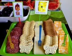 a green tray topped with different types of snacks and fruit on top of a table