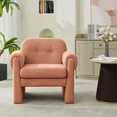 an orange chair in a living room next to a potted plant