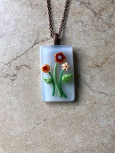 a glass pendant with flowers on it sitting on a marble counter top next to a chain