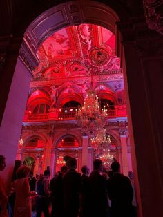 a group of people standing in front of a chandelier with red lights on it