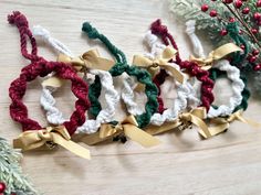 four crocheted christmas wreaths with bows and bells hanging on a wooden table