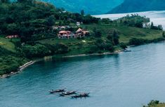 two boats are in the water near some hills and houses on a hill side, with mountains in the background