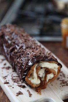 a chocolate covered pastry sitting on top of a wooden cutting board