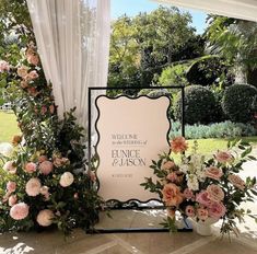 a welcome sign surrounded by flowers and greenery at a wedding ceremony in front of a gazebo