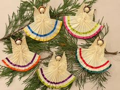 six handmade angel ornaments hanging from a pine branch