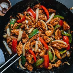 a pan filled with chicken and peppers on top of a table