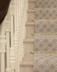 the stairs are decorated with gold rods and decorative wall hangings, along with beige fabric