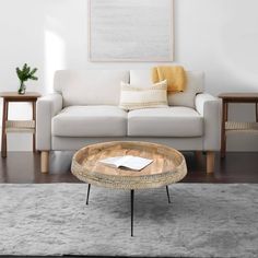 a living room with a white couch and coffee table in front of a painting on the wall