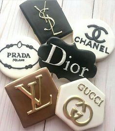 four decorated cookies with the letters dior and y in gold, black, and white