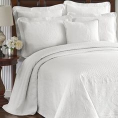 a bed with white comforter and pillows on it