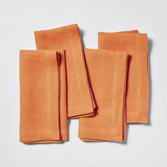 four orange linen napkins folded on top of each other