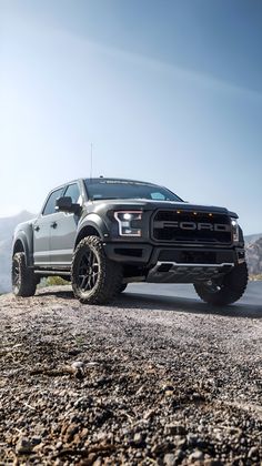 the truck is parked on the side of the road near some rocks and mountains in the background