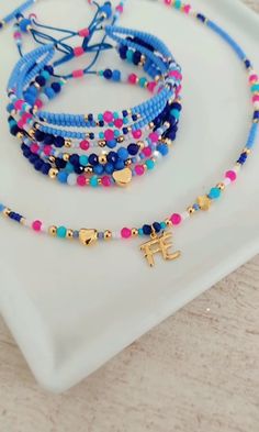 three beaded bracelets on a white plate with a blue cord and cross charm