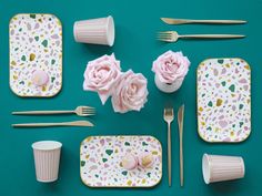 the table is set with pink flowers and gold cutlery, napkins, cups, and utensils