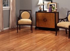 two chairs sitting on top of a hard wood floor next to a dresser and window