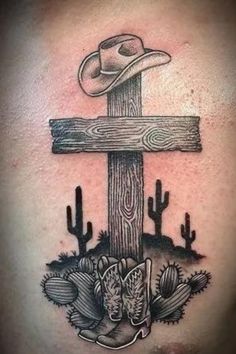 a cross with a cowboy hat on it and cactuses around the cross is shown