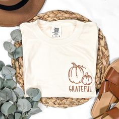 Celebrate the beauty of the autumn season with our fall shirt featuring a beautifully embroidered pumpkin design and the word, "grateful." This Christian graphic tee is soft, comfy and fits like a well-loved favorite. Whether you're looking for Thanksgiving apparel or a thoughtful birthday gift for a friend, this Comfort Colors T shirt is an ideal choice. This tee is embroidered in our shop in Kentucky. * Embroidered on an ivory long sleeve or short sleeve Comfort Colors tee * 100% ring-spun US cotton for long-lasting comfort * Relaxed unisex fit * Sewn-in twill label * Available in sizes S-3XL * Runs true to size - for an over-sized fit, go up a size or two * See last picture for size chart * Ships with tracking in 1-2 weeks Machine wash cold, inside out. Do not use bleach. Tumble dry low Cotton T-shirt For Everyday Fall Wear, Everyday Cotton T-shirt For Fall, White Tops With Embroidered Text For Fall, Embroidered Graphic Tee For Fall, Casual Tops With Custom Embroidery For Fall, Relaxed Fit Cotton T-shirt For Fall, Everyday Tops With Embroidered Text For Fall, Embroidered Text Tops For Everyday Fall Wear, Embroidered White T-shirt For Fall