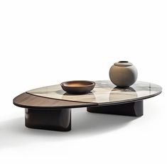 a glass table with two bowls on it and a vase sitting on top of it