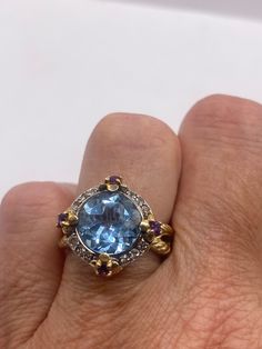 Huge great color blue topaz with garnets and white sapphires  stone surrounding setting is handcrafted in 925 sterling silver  size 5.5, 6, 6.5,or 7 Can be sized, our jeweler charges $20  All rings are shipped in a nice gift box.   Check out our over a THOUSAND great reviews Engraving is $4 per letter and is not always perfect depending on the piece. It can take a few days if the jeweler is busy. This is payable to Paypal Judithsltd@gmail.com  PLEASE NOTE If we have multiples of the same vintage Blue Gemstone Jewelry With White Topaz, Blue White Topaz Ring With Gemstone, Exquisite Blue Topaz Ring With Center Stone, Blue Gemstone Rings With White Topaz, Round Blue Topaz Set Ring, Multi-stone Blue Topaz Ring, Round Blue Topaz Ring With Stone Setting, Blue Topaz Round Ring, Blue Topaz Ring With Stone Setting