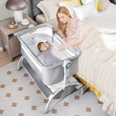 a woman standing next to a baby in a crib on top of a bed