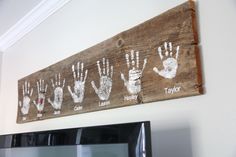 a wooden sign with handprints on it hanging from the wall above a microwave