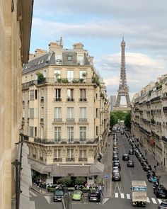 the eiffel tower is in the distance as cars drive down an empty street