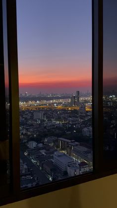 the view from an apartment window at sunset or dawn with city lights in the distance