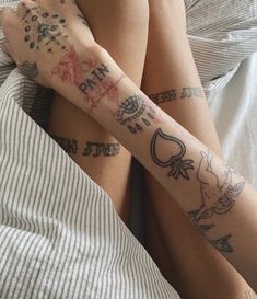 two people laying in bed with tattoos on their arms and legs, both holding each other's hands