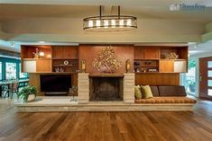 a living room with wood flooring and a fire place in the middle of it