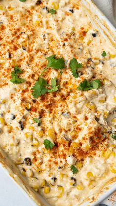 a casserole dish filled with corn, cheese and seasoning sprinkled with parsley