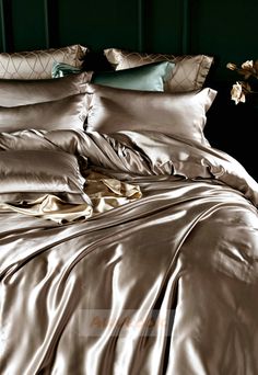 a bed with satin sheets and pillows on it