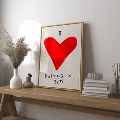 a red heart is displayed on a shelf next to a vase with flowers and books