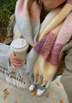 a woman holding a coffee cup and scarf