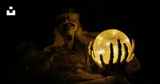 a creepy figure holding a glowing ball in the dark