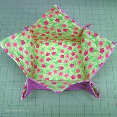 an origami flowered paper basket sitting on top of a piece of cloth