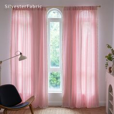 a living room with pink curtains and a chair