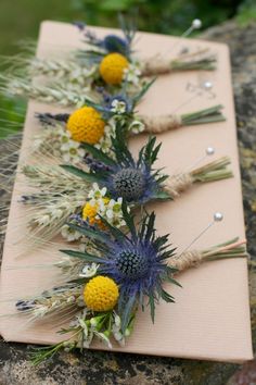 three flower arrangements are arranged on a piece of paper that is sitting on a rock