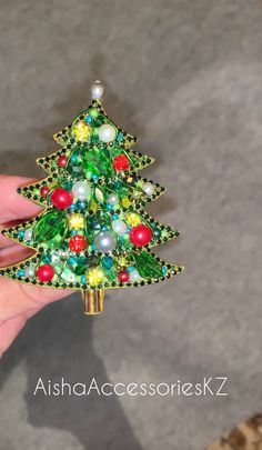 a hand holding a christmas tree brooch