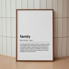 a white framed poster with the words family on it in front of a tiled wall