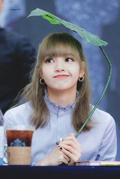 a woman sitting at a table with a plant on her head