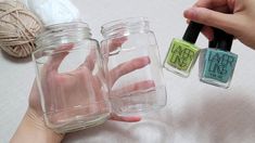 two jars with different colored nail polishes on top of each other, one being held up by someone's hand