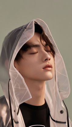 a young man with his eyes closed wearing a clear raincoat