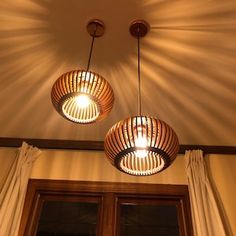 two wooden lights hanging from the ceiling above a window